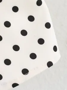 Detailed macro view of white fabric with black polka dots and precise stitching finish