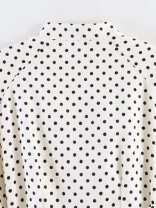 Detailed view of white fabric with black polka dots showing high-quality stitching