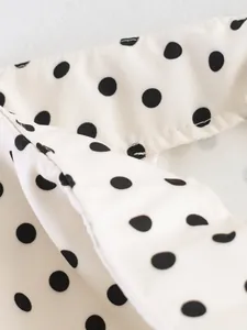 Macro detail of white fabric with black polka dots showing seam construction
