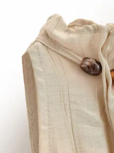 Dettaglio del top a lupetto beige con perle decorative sullo scollo.