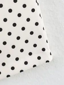 Close-up detail of black polka dot pattern on white elastic fabric with stitched hem