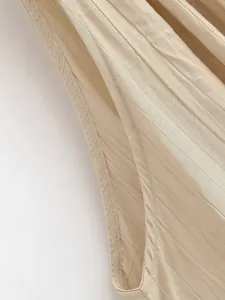 Primo piano dettagliato del tessuto strutturato beige e delle cuciture del capo.