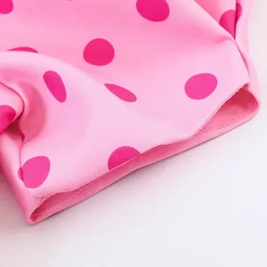 Detailansicht von rosa gepunktetem Stoff mit feinen Nähten an einem Puffärmel.