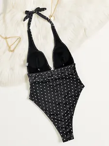 Vista posteriore di un costume da bagno intero a pois neri con scollo all'americana e fiocco