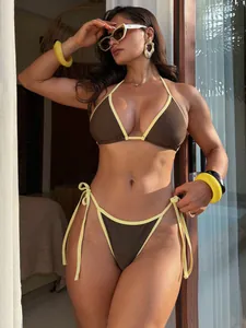 Set bikini halter marrone e giallo a contrasto indossato da una modella in un resort.