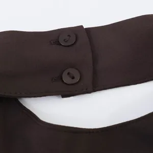 Detailaufnahme eines kaffeebraunen Neckholder-Tops mit Knopfverschluss und Kreppstoff.