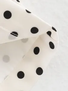 Macro shot of black polka dot pattern on white fabric showing high-quality stitching