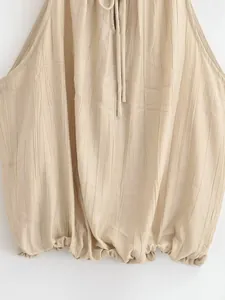 Dettaglio di un top a fascia plissettato beige con orlo a palloncino e dettaglio laccetti.