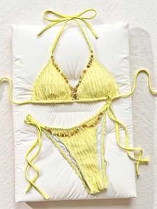 Close-up detail view of yellow textured bikini set with decorative amber stone beading