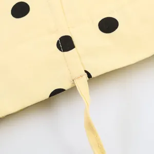 Detailaufnahme des gelben Polka-Dot-Stoffs mit hochwertigen Nähten und Kordelzug