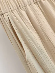 Dettaglio ravvicinato di pantaloni plissettati beige con tasca e trama fine.