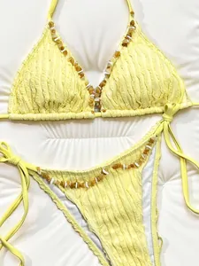 Close-up of yellow ruffled bikini set with decorative beaded stone embellishments