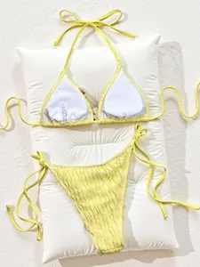 Detailed view of yellow textured bikini set with adjustable tie strings on white cushion