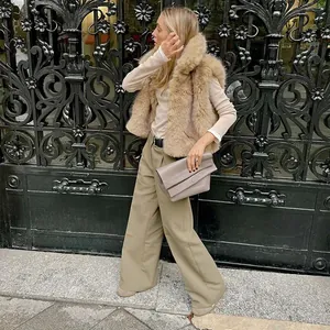 Mujer elegante con un chaleco de piel sintética beige y pantalones de pata ancha