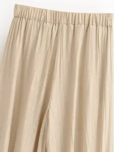 Primo piano di pantaloni a lanterna plissettati beige con vita elastica confortevole.