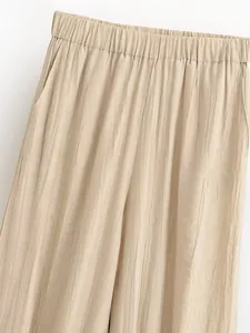 Dettaglio ravvicinato di pantaloni plissettati beige con vita elastica e tasche