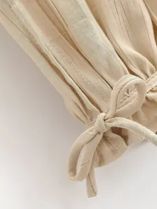 Dettaglio del tessuto a coste beige e del polsino con fiocco sui pantaloni moda.