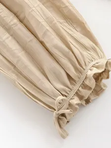 Dettaglio di tessuto plissettato beige con orlo a balze e fiocco