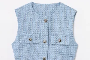 Nahaufnahme einer hellblauen Tweed-Weste mit glänzenden Metallknöpfen und Pailletten