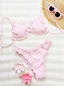 Detailed view of pink ruffled bikini set with elegant pleated texture and floral props