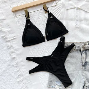 Flat lay detail of a black sexy hollow-out bikini set with metal ring accents