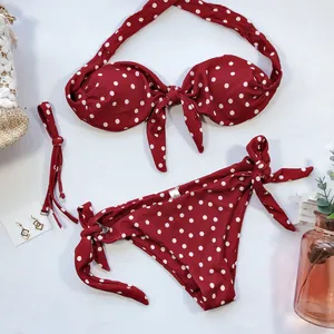 Gros plan d'un ensemble bikini rouge à pois blancs avec détails de nœuds sur un fond blanc.