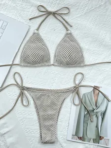 Detailed view of khaki crochet mesh bikini set laid flat on white textured fabric background
