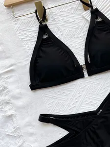 Close-up detail of sexy black hollow-out bikini set with silver rings on white towel.
