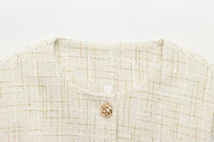 Nahaufnahme der cremefarbenen Tweed-Weste mit elegantem goldenem Knotenknopf-Detail.
