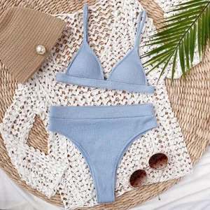 Conjunto de bikini azul claro con top de triángulo y corte alto sobre esterilla playa