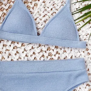 Primer plano detallado de bikini de canalé azul claro en un fondo tropical de verano chic