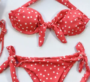 Gros plan d'un ensemble bikini rouge à pois blancs avec nœuds et tissu texturé.