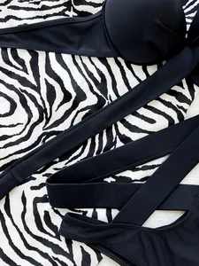 Close-up detail of black high-waisted bandage bikini set on zebra print background