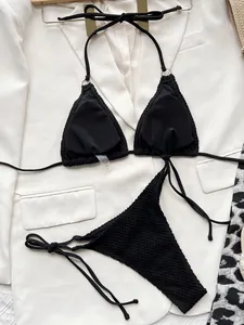 Close-up of black mesh texture triangle bikini set on white blazer background