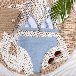 Vista detallada de un conjunto de bikini acanalado azul claro sobre un tapete de paja