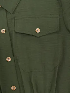 Close-up view of the green linen fabric and pocket detail of the jumpsuit