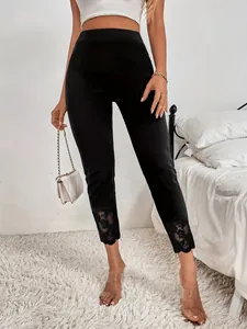 Détail de leggings noirs ajustés avec élégant empiècement en dentelle florale à l'ourlet