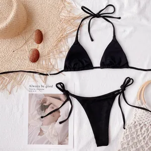 Elegant classic black string bikini set laid flat on white textured fabric background.