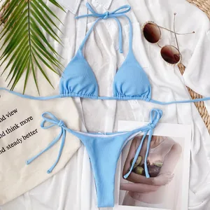 Top view of a light blue ribbed triangle bikini set with white shirt and beach accessories