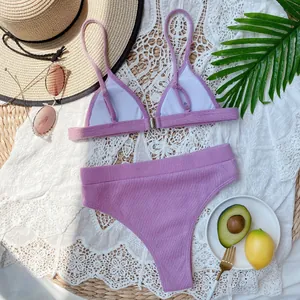 Primer plano de un conjunto de bikini morado acanalado de talle alto con accesorios.