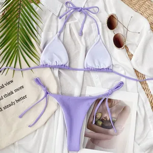 Flat lay detail of a purple ribbed triangle bikini set with lifestyle props