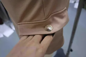 Close-up detail of khaki knit cargo skirt featuring functional pocket and button