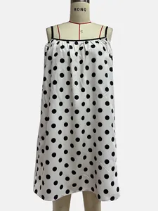 Detail view of a white summer dress with large black polka dots on a mannequin