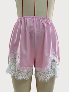Detailed view of pink satin loungewear shorts featuring white floral lace hem decoration.