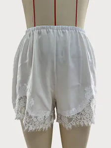 Detailed view of white satin shorts with intricate lace trim at the hem