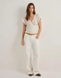 Detail of white floral lace short sleeve top with V-neck and sheer mesh texture
