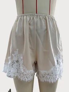 Detailed view of champagne satin shorts with elegant white lace trim hem