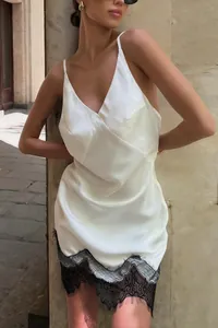 Elegante witte satijnen slipdress met V-hals en verfijnde zwarte kanten zoomdetails.