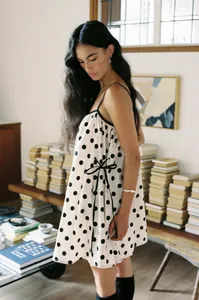 Lifestyle view of a women's black and white polka dot sleeveless summer mini dress