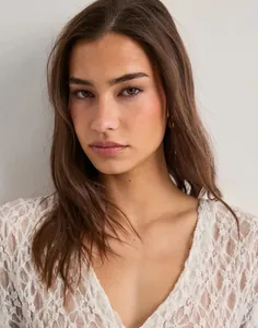 Close-up detail of white floral lace pattern on sexy Y2K sheer mesh V-neck top